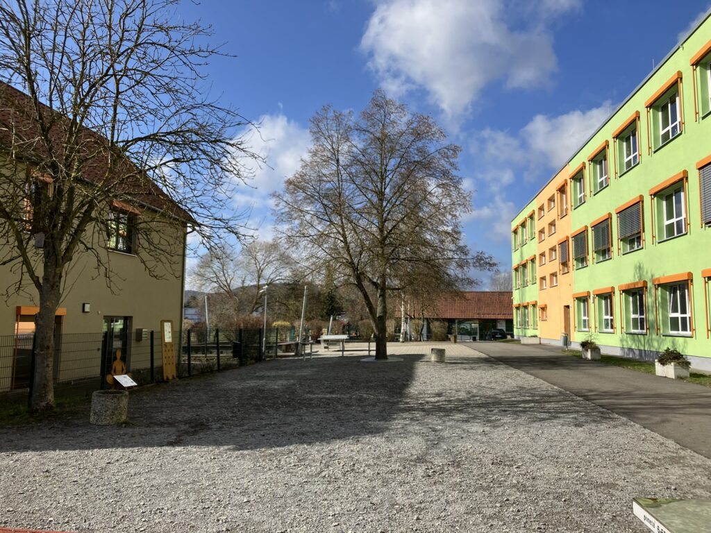 Blick auf den Zustand vor Sanierung auf die Regelschule Obermaßfeld mit Sporthalle und Außenanlagen.