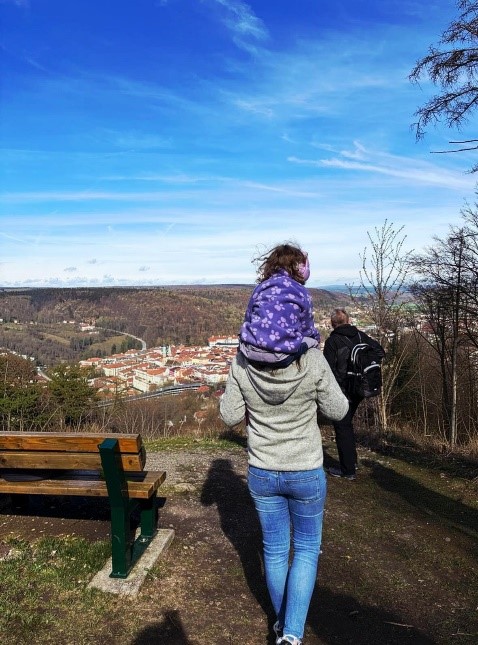 Eine Mutter trägt ihre Tochter auf den Schultern. Zusammen mit den Großeltern schauen sie von der Ruine Donopskuppe aus auf die Stadt Meiningen.