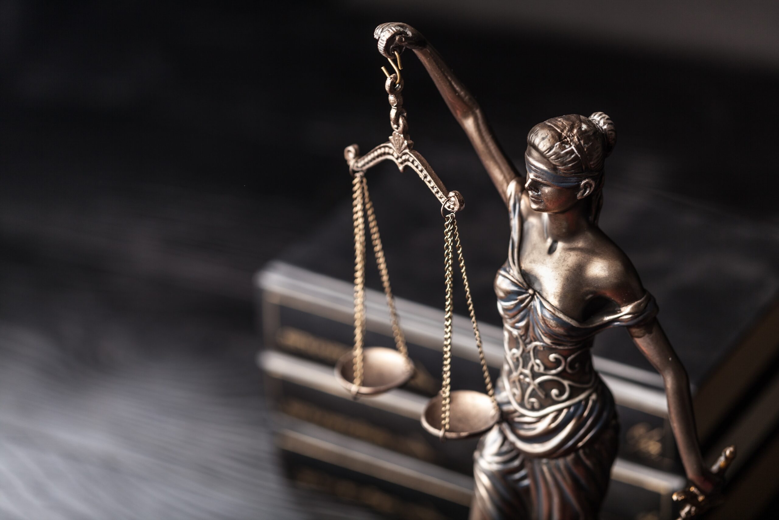Kleine Statue der römischen Göttin Justitia auf einem Tisch mit Büchern